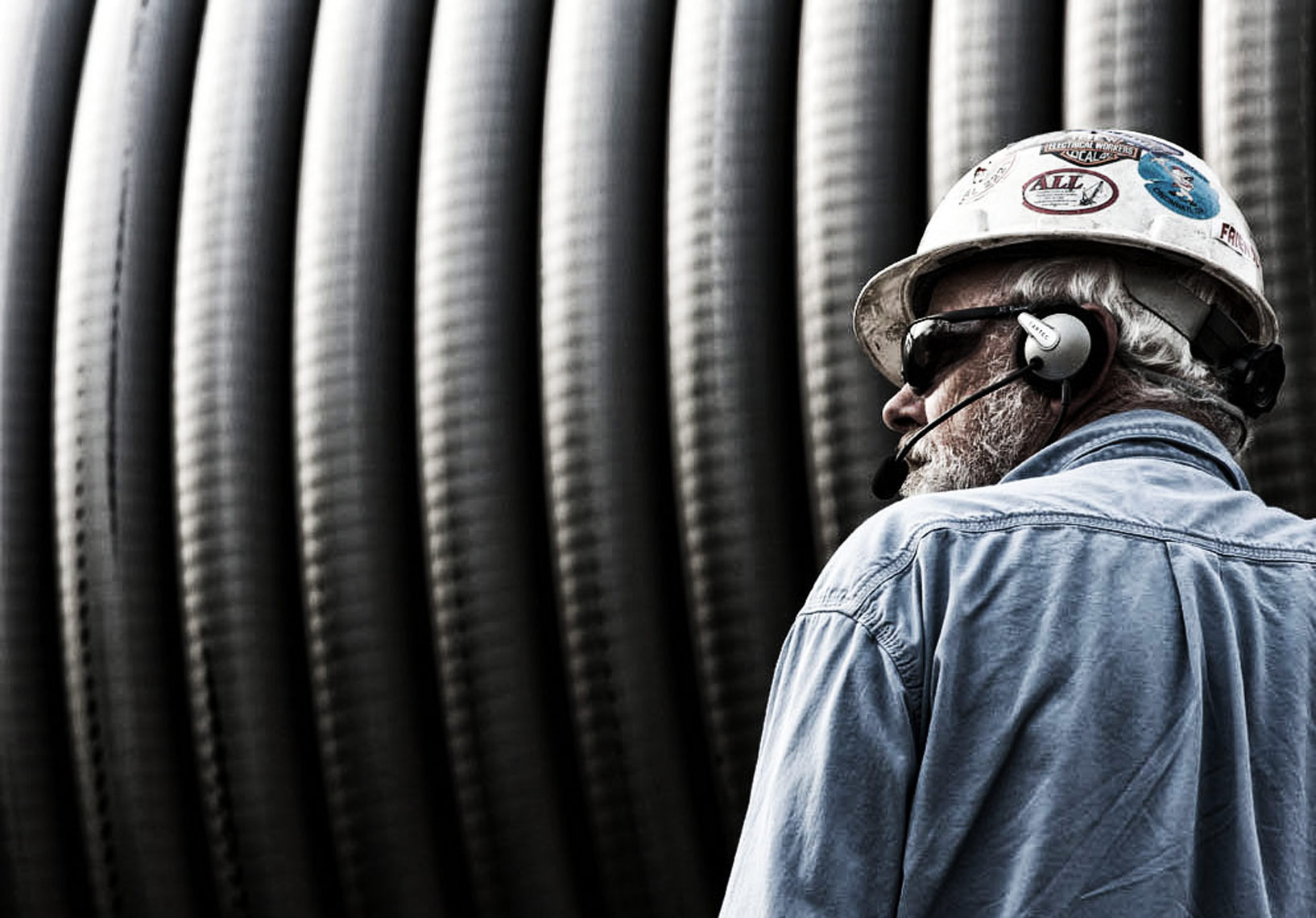 Industrial photo of man with large spool of cable
